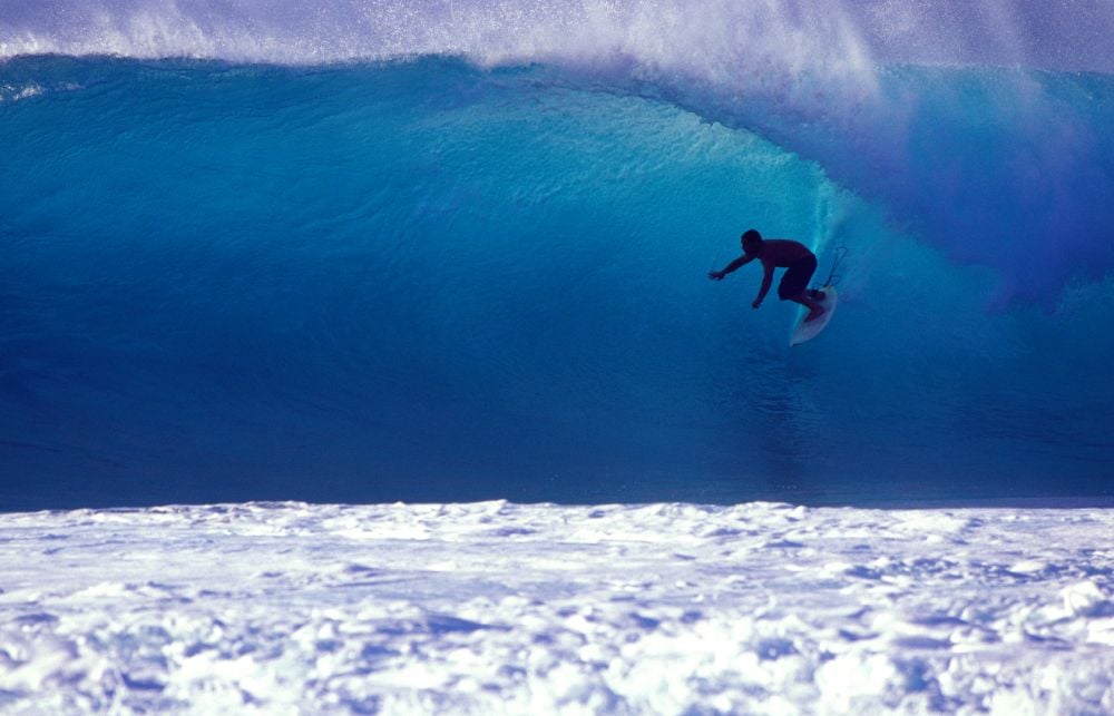 surfer on a backlit blue wave, getting barrelled on hawaii's north shore