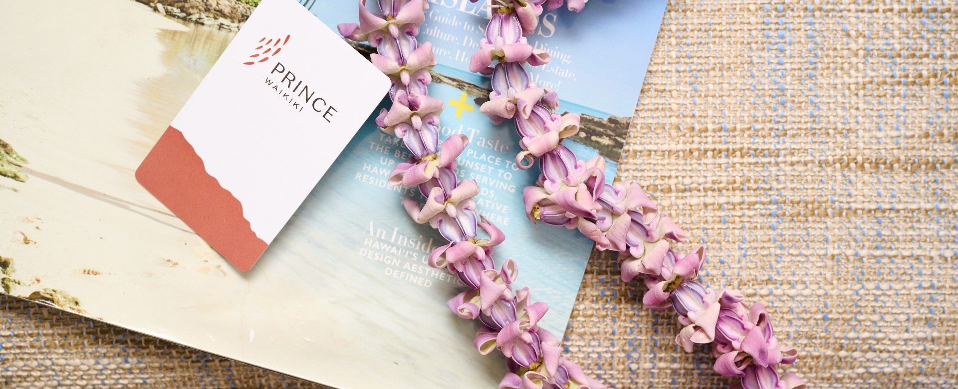 Room key and flower necklace on a strawgrass placemate