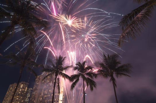 New Year's Eve fireworks framed by palm trees on Waikiki Beach in Honolulu, Hawaii