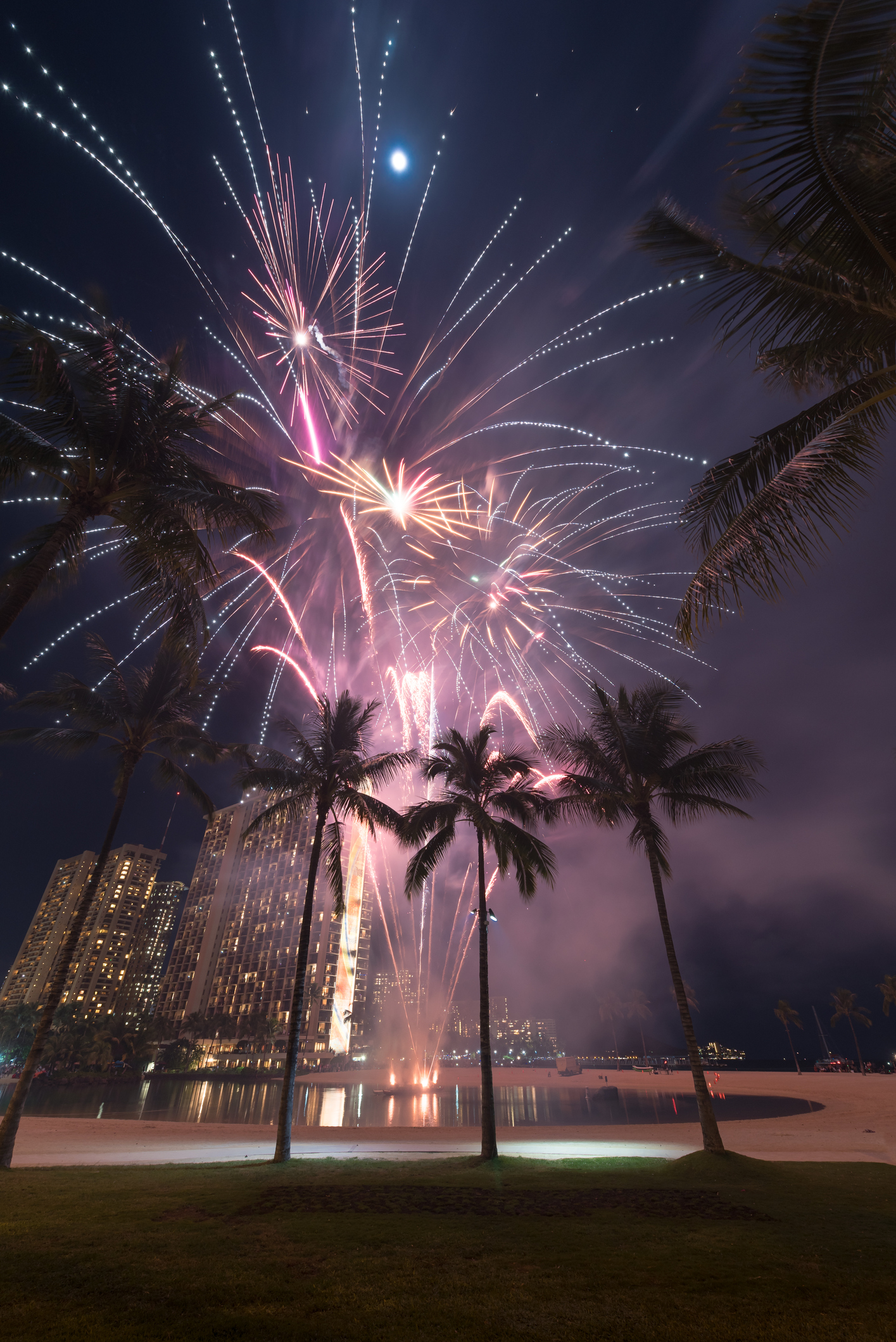 New Year's Eve fireworks framed by palm trees on Waikiki Beach in Honolulu, Hawaii
