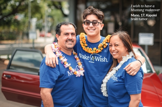 Make a Wish Hawaii photo with a son with his arms around his father and mother posing in front of a red car.