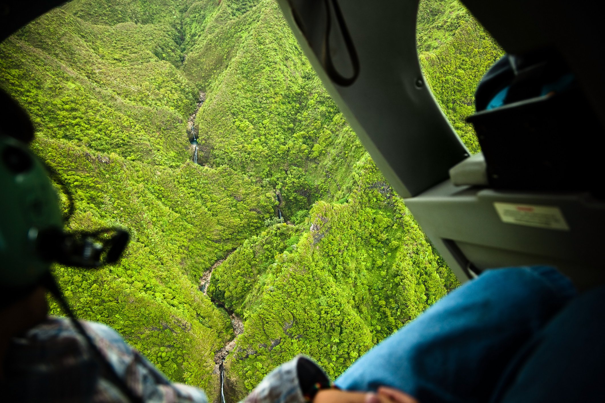 Helicopter ride with open doors over Sacred Falls State Park on Oahu, Hawaii.