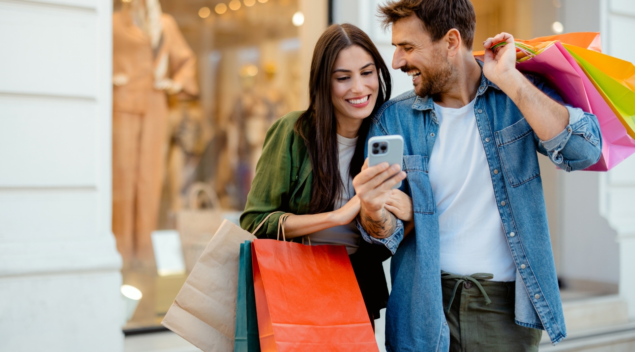 Young Happy Couple With Smart Phone and Shopping Bags