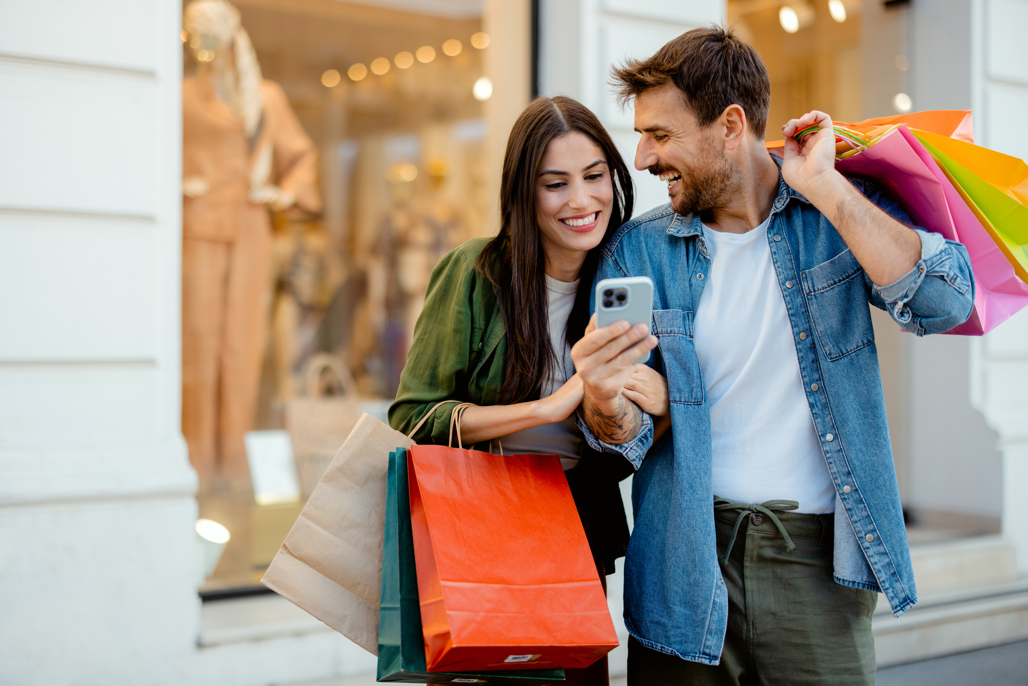 Young Happy Couple With Smart Phone and Shopping Bags
