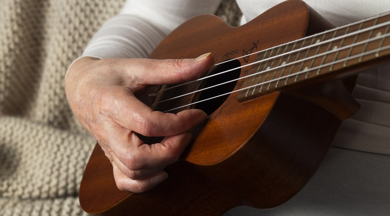 Close-up of hands playing guitar. musician playing hawaiian ukulele.